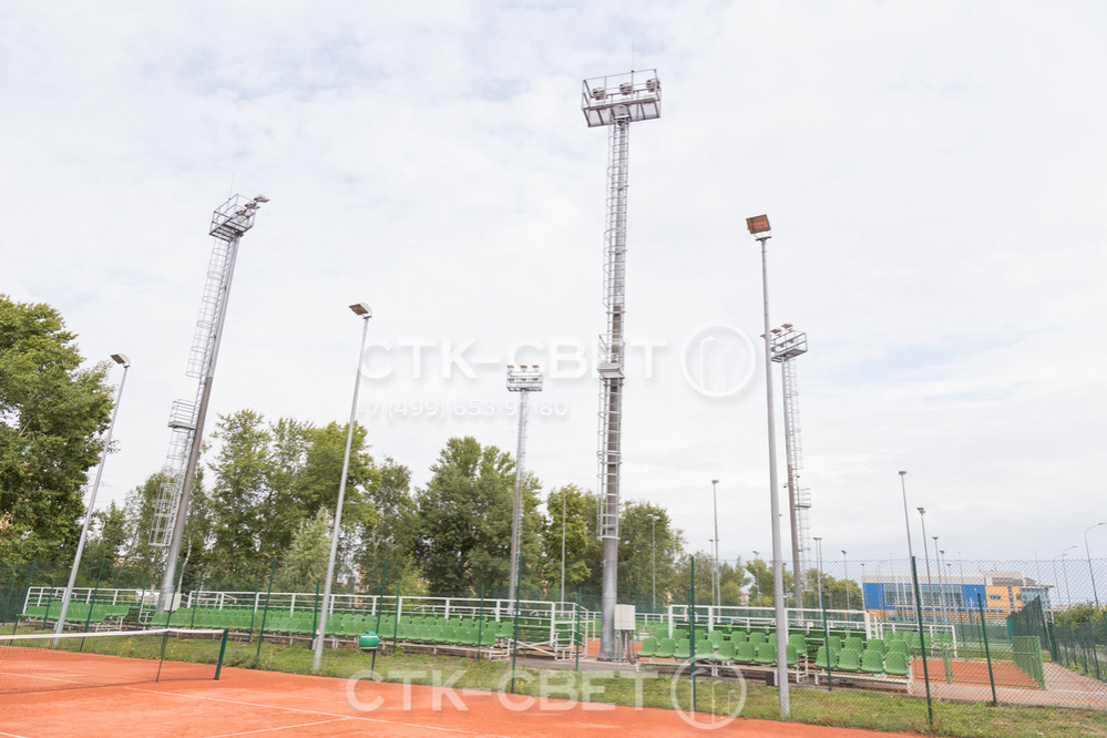 На фото изображены мачты со стационарной короной, которые используются для освещения теннисных кортов. Доля их обслуживания не нужно использовать АГП, которые не смогут подъехать к нужному месту, не испортив корт.