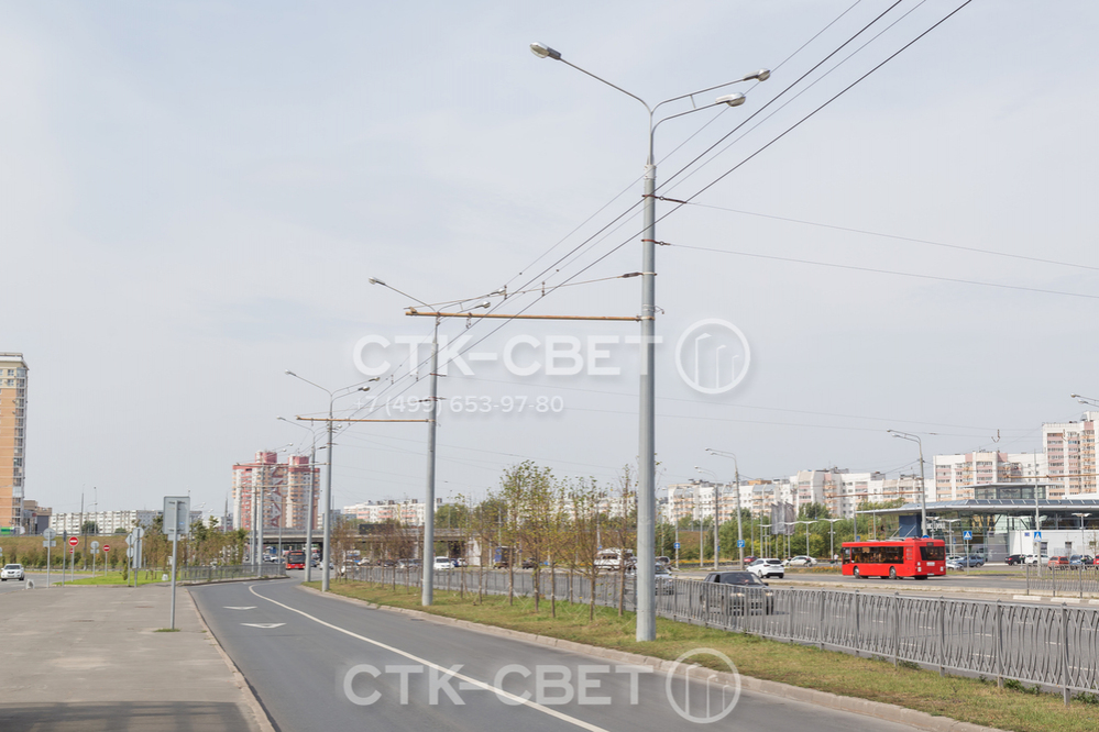 Опоры на фото используются для удержания контактной сети троллейбусов. Два светильника с одной стороны ярко освещают магистраль общего пользования, а один с противоположной стороны – служебную дорогу для электротранспорта.
